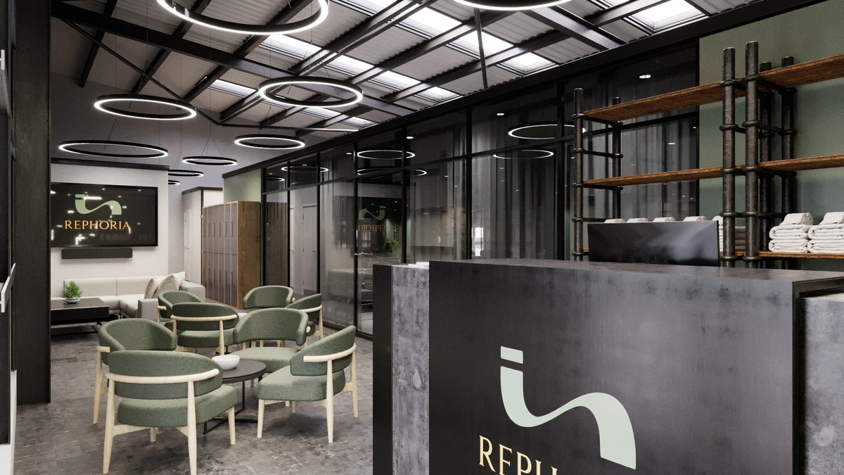 Rephoria reception desk featuring branding next to an industrial office waiting area with green chairs.
